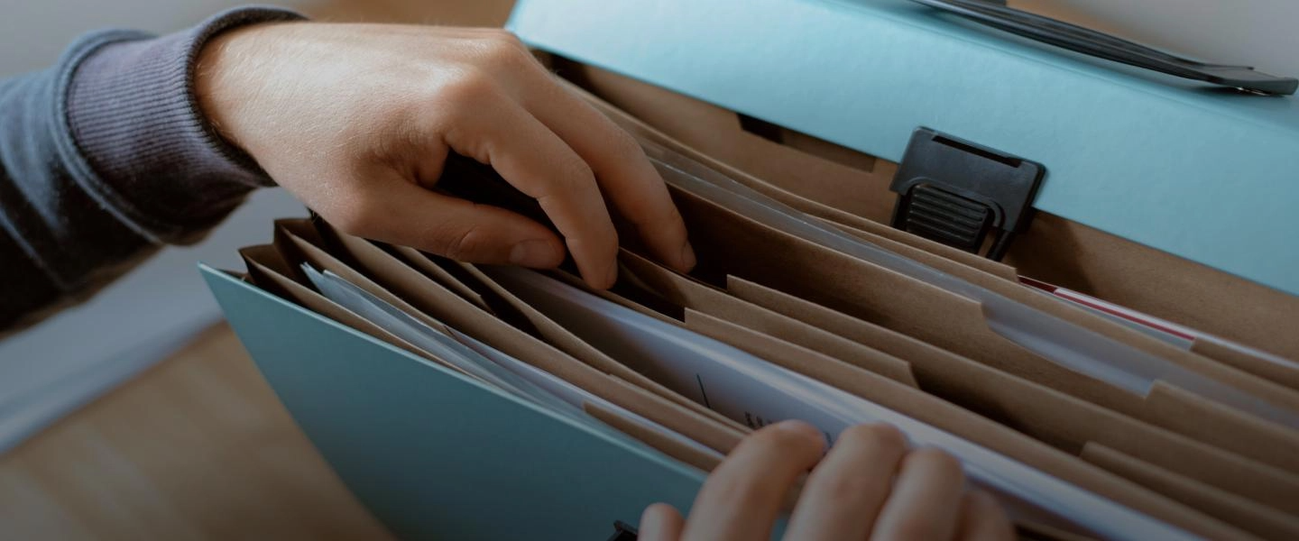 Manos buscando un documento dentro de una carpeta de archivo