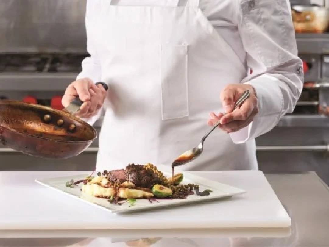 Persona con bata blanca preparando un platillo dulce hecho con los insumos culinarios para negocios de Nestlé.