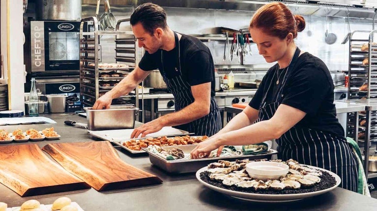 Dos chefs en la cocina de un restaurante preparando el buffet