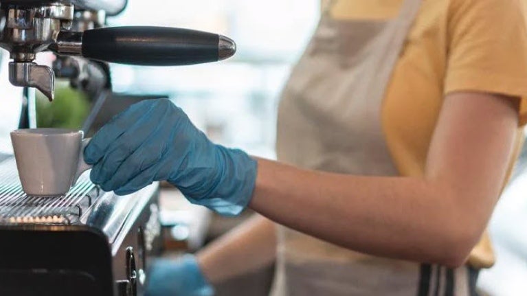 Barista manipulando bebida de café con guantes azules