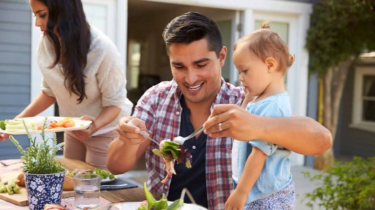 Papá come con su hija y familia al aire libre para celebrar el Día del Padre
