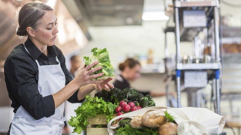 Chef revisa una lechuga y otras frutas y verduras antes de desinfectar en la cocina de un restaurante