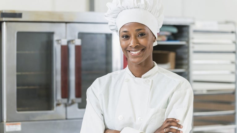 Mujer en una cocina comercial sonriendo en su emprendimiento de negocio de comida