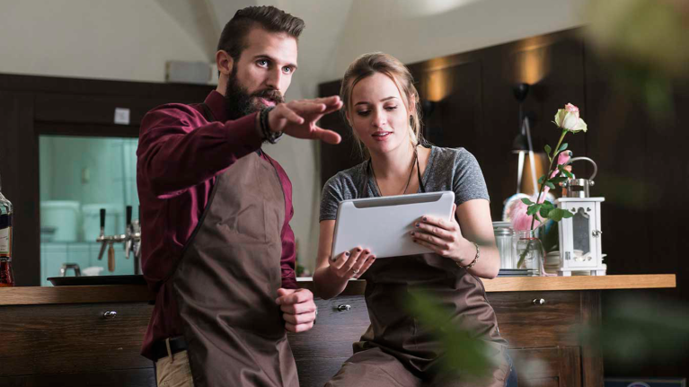 Dos empleados tomando decisiones a partir de una IA para restaurantes que consultan en una tablet