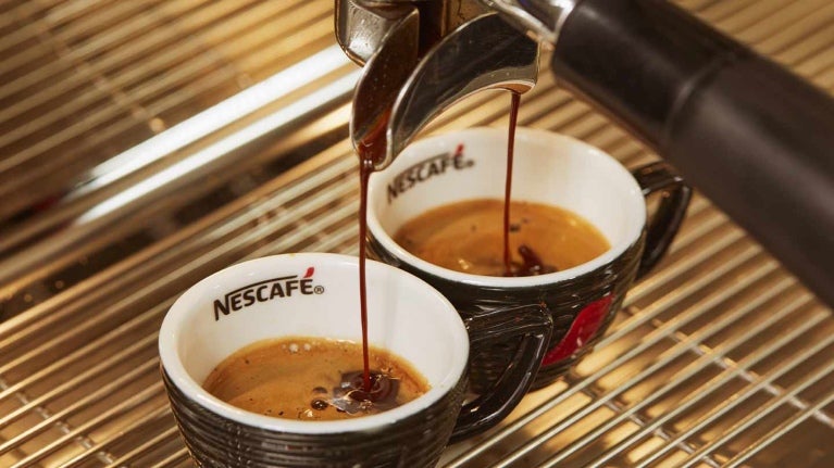 Filtro de una máquina vierte a presión café sobre dos tazas de NESCAFÉ®