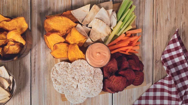 Chips de camote, remolacha, bastones de vegetales y salsa como snacks para cafetería