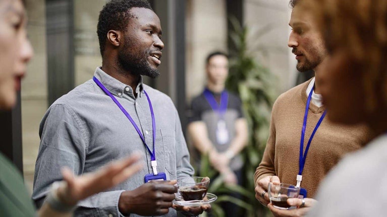 Grupo de trabajadores conversan mientras disfrutan de una taza de café durante un coffee break