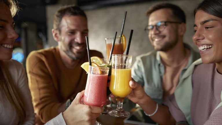 4 amigos felices brindan con mocktails de frutas en un negocio de food service