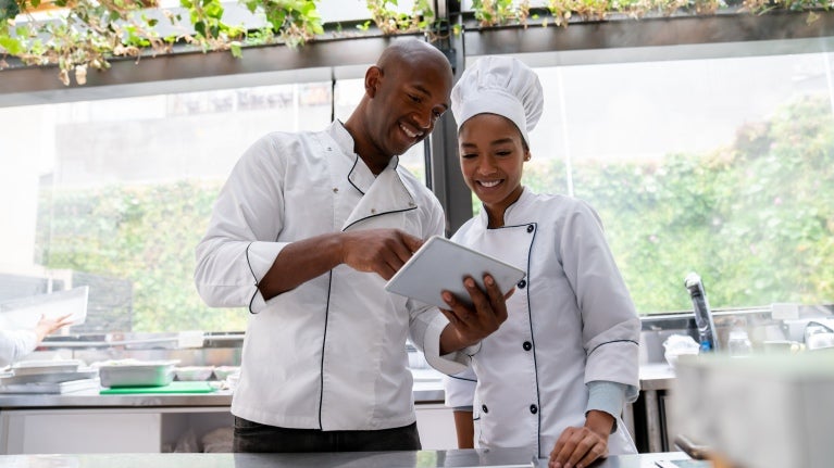 Dos chefs mirando una tablet, usan aplicaciones para crear recetas con IA