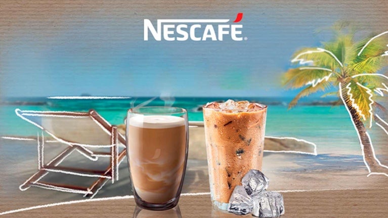 Dos vasos de café frío con leche y hielo elaborados con NESCAFÉ®. Al fondo una playa