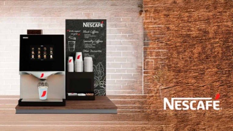 Máquina de café NESCAFÉ® en un cover con vasos, tapas, endulzantes y material POP