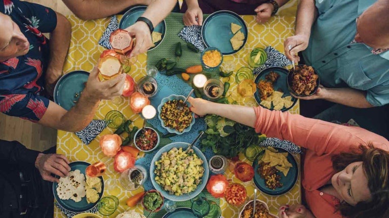 Grupo de personas celebra una fecha especial, comiendo y brindando a la mesa de un restaurante