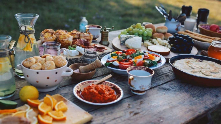 Mesa con diferentes tipos de comidas y bebidas, servida al aire libre