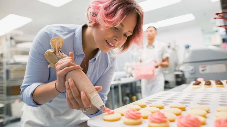 Mujer poniendo crema batida a un aperitivo de boda.