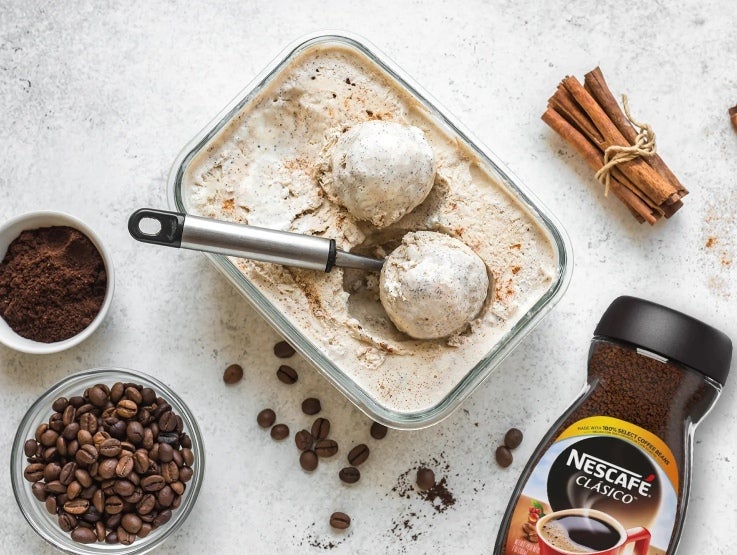 Recipiente con helado y alrededor tazas con café en grano, molido y NESCAFÉ® Clásico