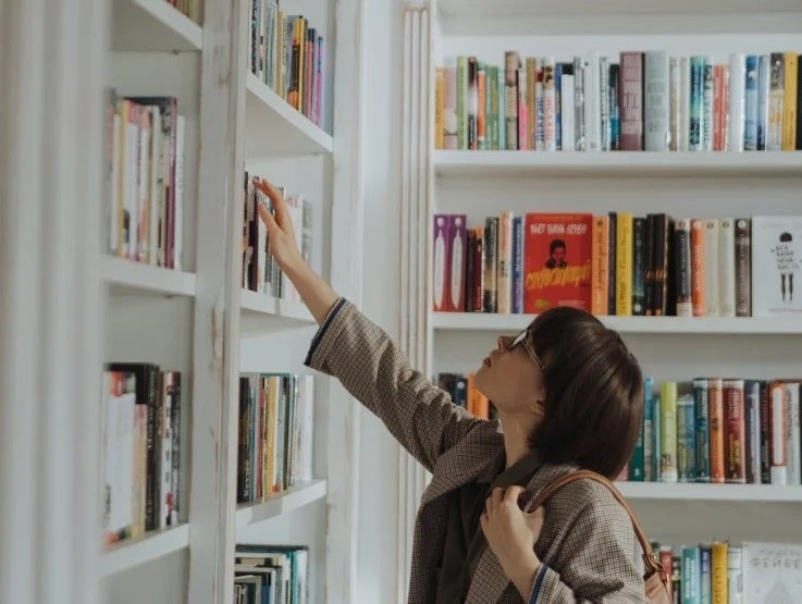 Mujer tomando un libro de la biblioteca