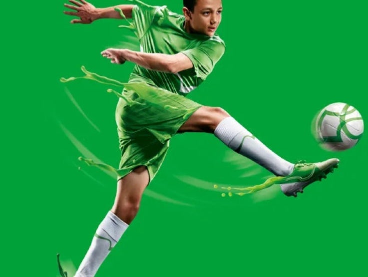 Jugador de fútbol vestido con un uniforme del color de la marca MILO® patea un balón