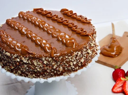 Sobre una mesa, Torta de pecanas decorada con Manjar NESTLÉ® y chocolates