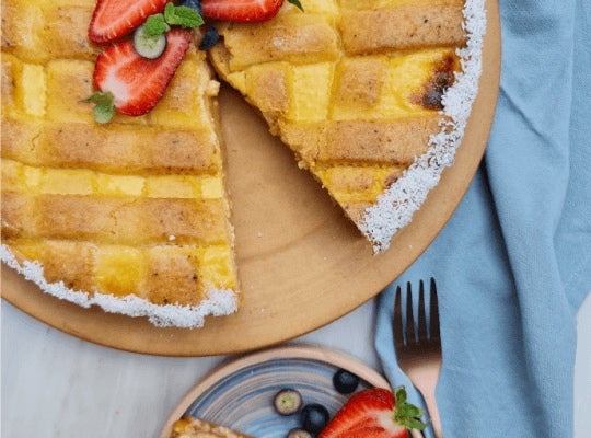 Sobre una base de madera, una Tarta de ricotta y NESTLÉ® Manjar Dulce de Leche sin un trozo