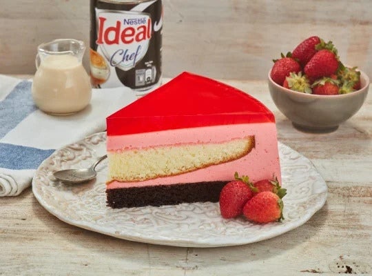 Trozo de Torta Helada con Gelatina de frutos rojos y fresas servidas a la mesa junto a la IDEAL® Cremosita