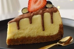 Porción triangular de Cheesecake de Kit Kat adornado con media fresa